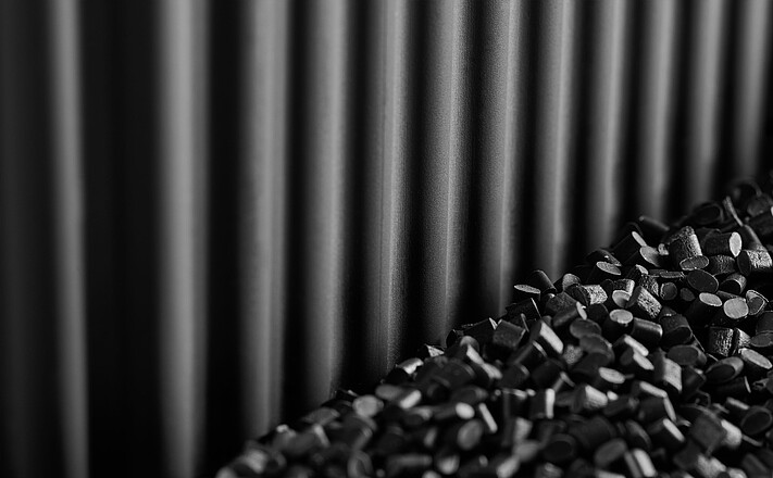 Struktur des Greenling-Blumenkastens Kobold aus schwarzem Recyclinggranulat, mit Granulat vor dem Blumenkasten